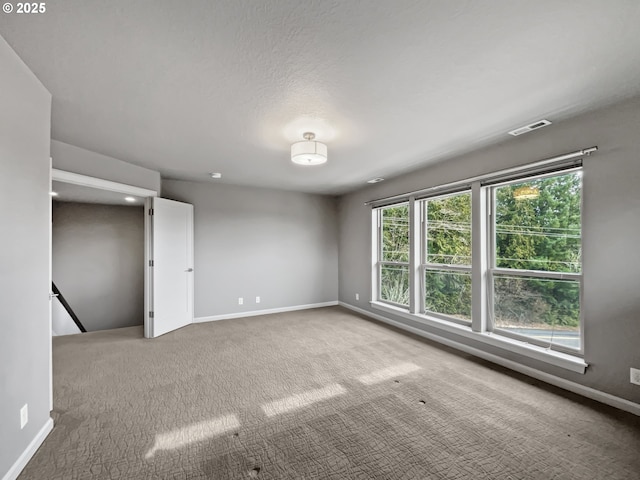 carpeted empty room with visible vents and baseboards