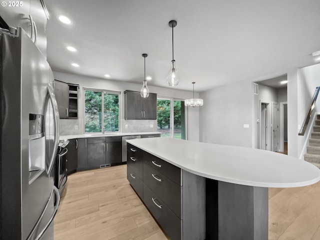 kitchen with light wood-type flooring, a kitchen island, stainless steel appliances, light countertops, and tasteful backsplash