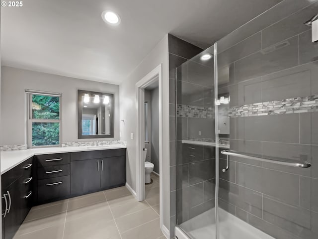 bathroom featuring tile patterned flooring, a shower stall, toilet, and vanity