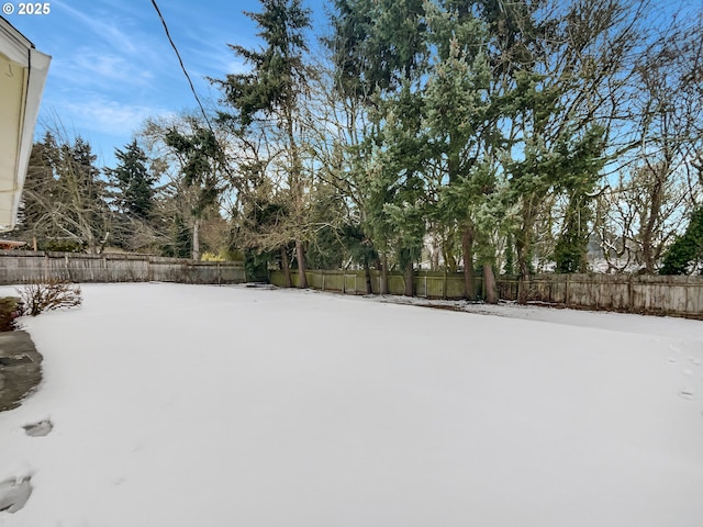 snowy yard featuring a fenced backyard