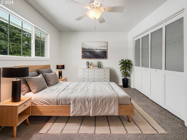 carpeted bedroom featuring a textured ceiling and a ceiling fan