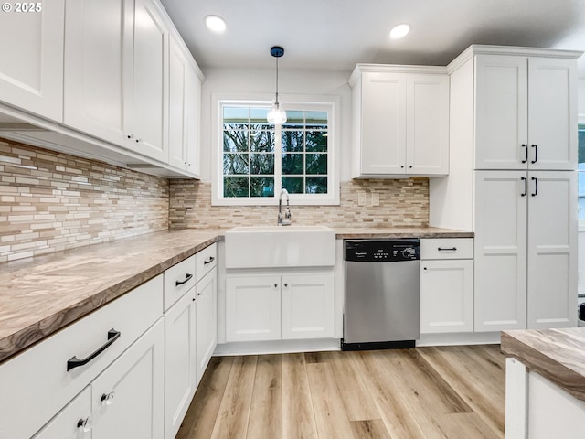 kitchen with white cabinetry, a sink, light wood-style floors, pendant lighting, and stainless steel dishwasher