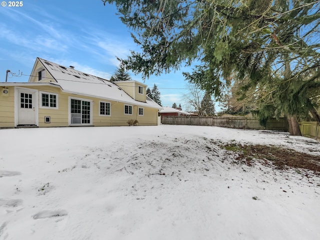 snow covered rear of property with fence