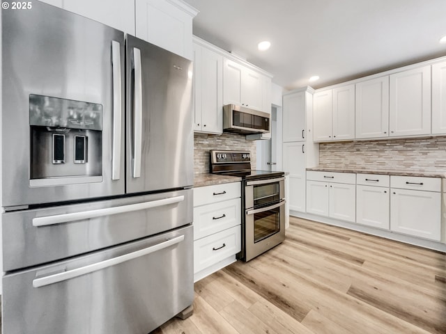 kitchen featuring light wood-style flooring, tasteful backsplash, white cabinets, and stainless steel appliances