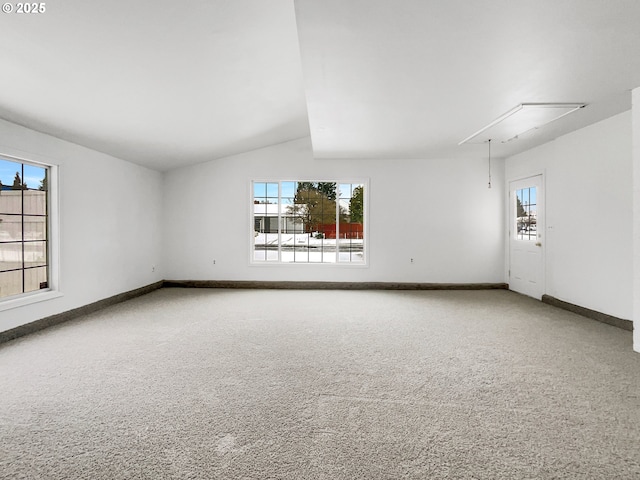 carpeted empty room with baseboards, a healthy amount of sunlight, attic access, and lofted ceiling