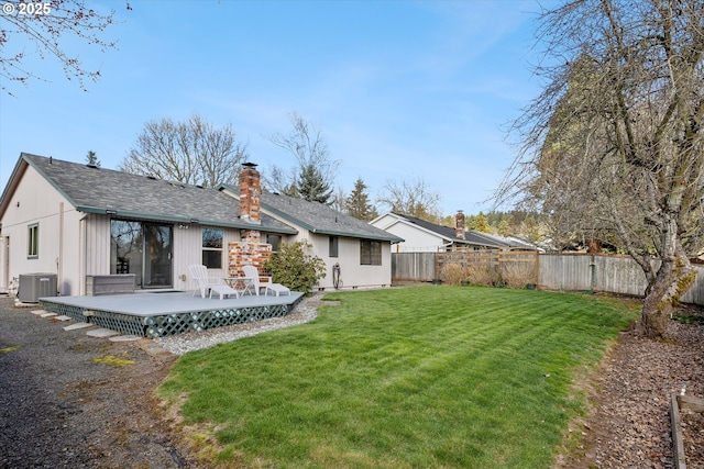 back of property featuring a yard, a chimney, central AC, a deck, and a fenced backyard