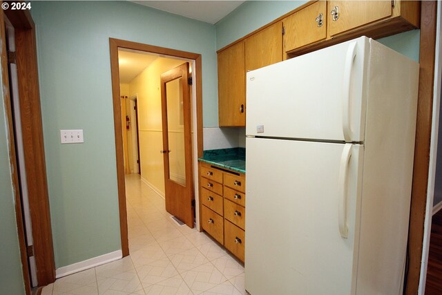 2309 SE 90th Ave, Portland, OR 97216 - kitchen with freestanding refrigerator, dark countertops, baseboards, and brown cabinetry