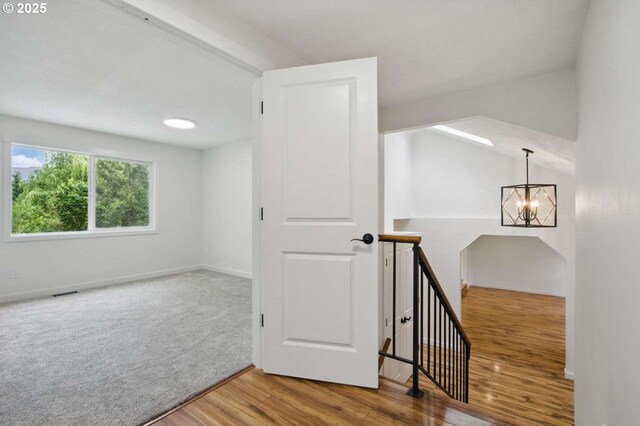 bonus room with wood finished floors, a chandelier, and baseboards