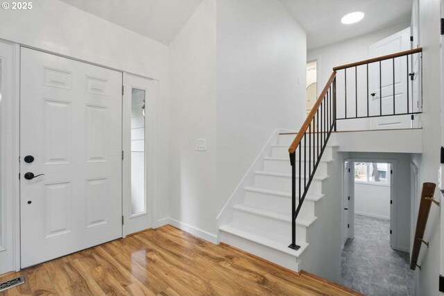 entrance foyer featuring light wood-style flooring, baseboards, and stairway