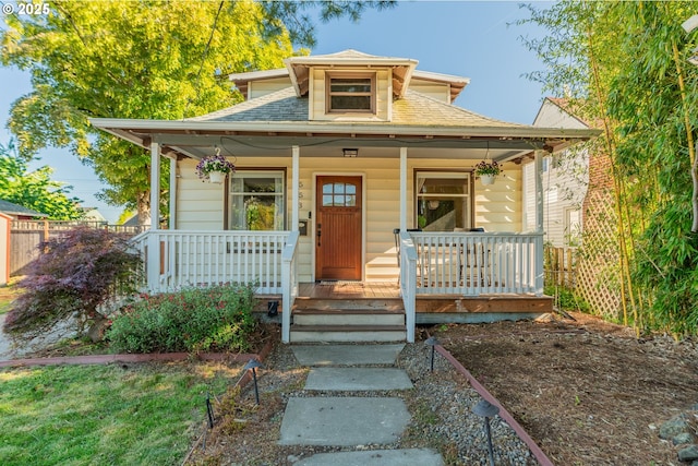 bungalow with covered porch and a shingled roof