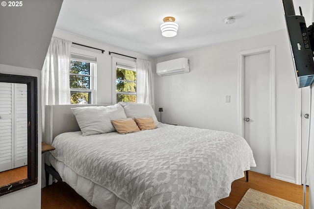bedroom with a wall unit AC and wood finished floors