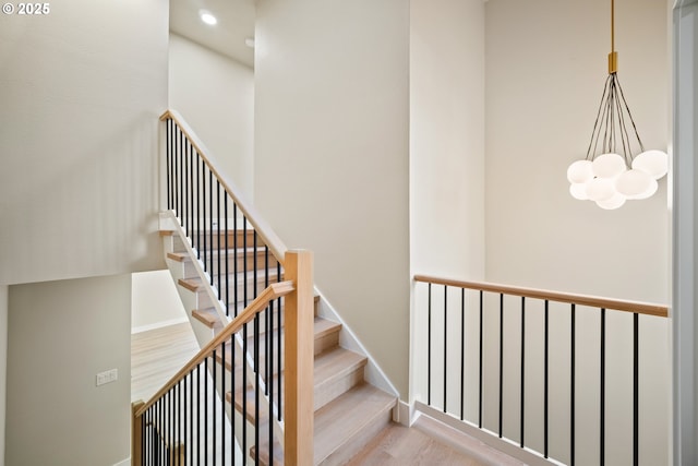 stairway with hardwood / wood-style flooring and a notable chandelier