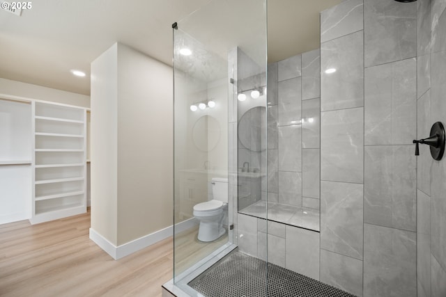 bathroom featuring hardwood / wood-style flooring, toilet, and a tile shower