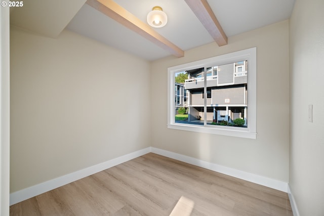 unfurnished room with beam ceiling and light wood-type flooring