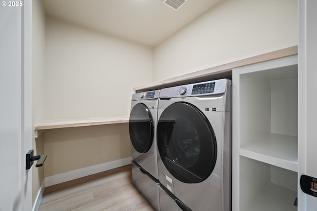 clothes washing area with separate washer and dryer and light hardwood / wood-style flooring