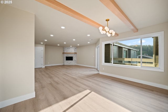 unfurnished living room featuring a notable chandelier, beam ceiling, light hardwood / wood-style floors, and a fireplace