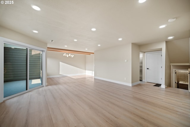 spare room featuring an inviting chandelier and light wood-type flooring