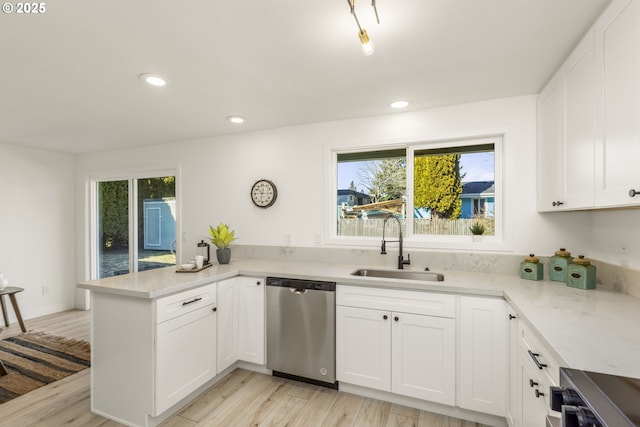 kitchen with sink, white cabinets, stainless steel dishwasher, kitchen peninsula, and plenty of natural light