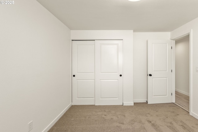 unfurnished bedroom featuring light colored carpet and a closet