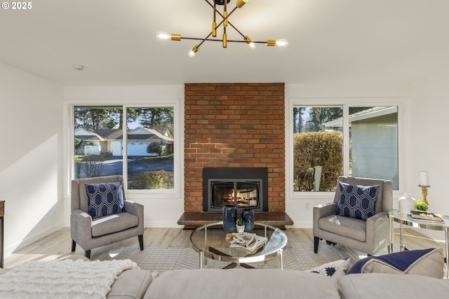 living room featuring a brick fireplace, a notable chandelier, and light hardwood / wood-style flooring