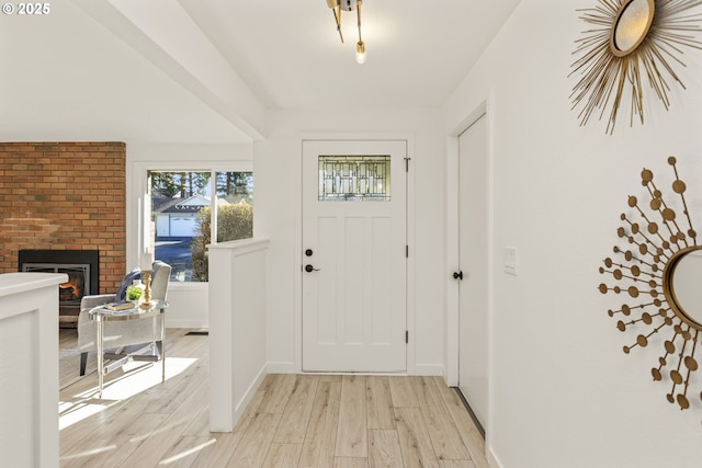 entrance foyer with light hardwood / wood-style floors and a brick fireplace