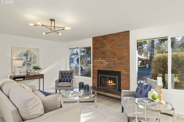 living room with a chandelier, a fireplace, and light hardwood / wood-style flooring