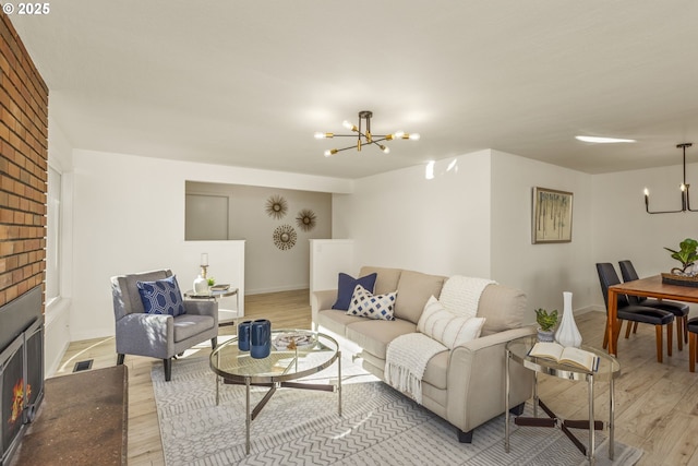 living room featuring a fireplace, a chandelier, and light wood-type flooring