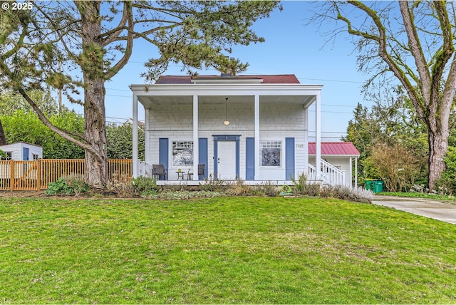 view of front of home with covered porch, metal roof, fence, and a front lawn