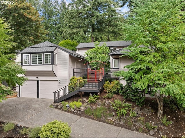 view of front of home with a garage, concrete driveway, and roof with shingles