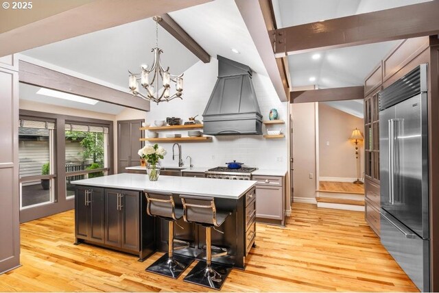 kitchen with built in refrigerator, custom range hood, lofted ceiling with beams, and open shelves