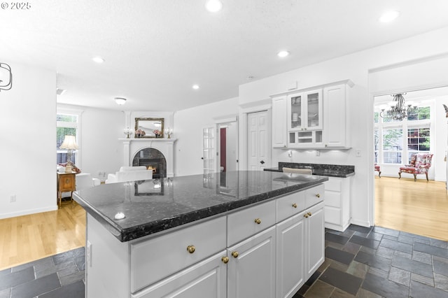 16800 NW Paddington Dr, Beaverton, OR 97006 - kitchen featuring white cabinetry, recessed lighting, a center island, a lit fireplace, and glass insert cabinets