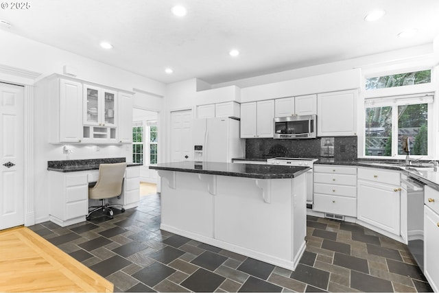 16800 NW Paddington Dr, Beaverton, OR 97006 - kitchen featuring stainless steel appliances, a kitchen bar, white cabinets, a center island, and built in desk