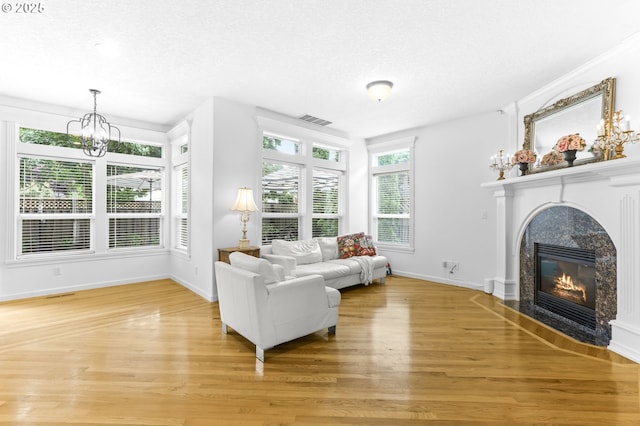 16800 NW Paddington Dr, Beaverton, OR 97006 - living room featuring light wood-type flooring, a chandelier, a textured ceiling, and a high end fireplace