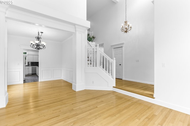 16800 NW Paddington Dr, Beaverton, OR 97006 - foyer with a chandelier, stairs, light wood-style floors, a wainscoted wall, and a decorative wall