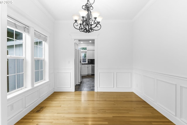 16800 NW Paddington Dr, Beaverton, OR 97006 - unfurnished dining area with a chandelier, a decorative wall, ornamental molding, wood finished floors, and wainscoting