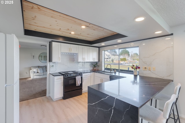 kitchen featuring sink, black range with electric stovetop, light hardwood / wood-style floors, white cabinets, and white fridge