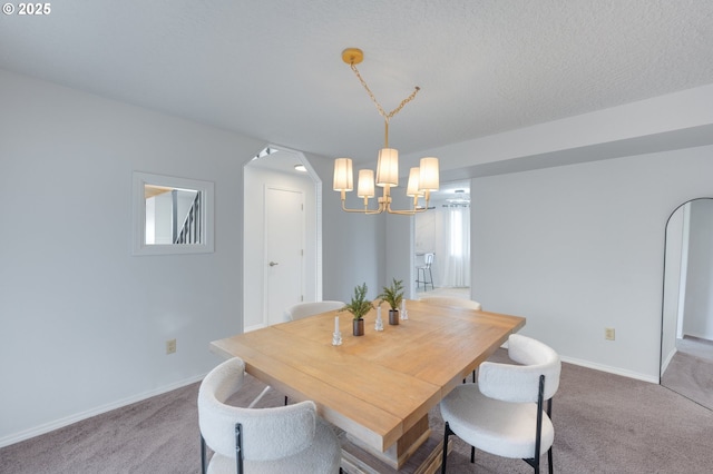 carpeted dining room featuring a notable chandelier and a textured ceiling