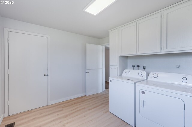 washroom featuring cabinets, washer and dryer, and light wood-type flooring