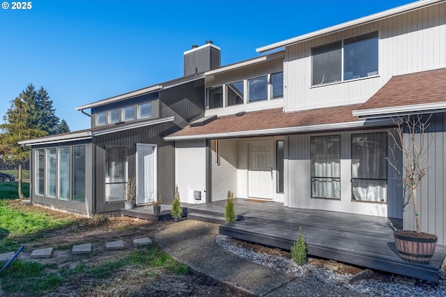 back of property with a wooden deck and a sunroom