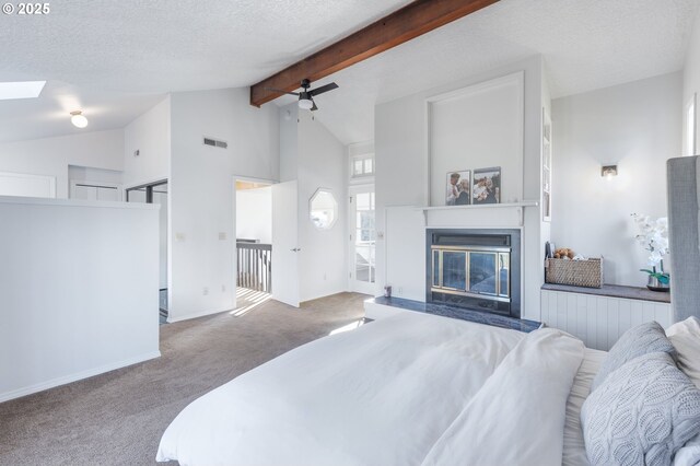 carpeted bedroom featuring ceiling fan, vaulted ceiling with skylight, and a textured ceiling