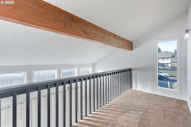 hall featuring plenty of natural light, carpet flooring, vaulted ceiling with beams, and a textured ceiling