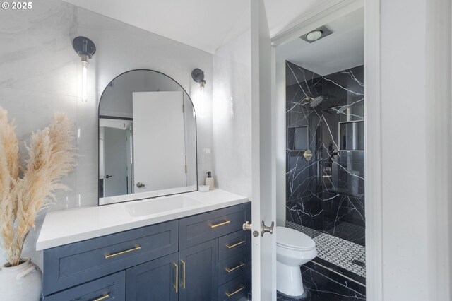 bathroom with vanity, toilet, and tiled shower