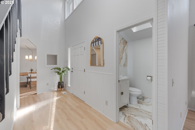 interior space featuring toilet, hardwood / wood-style floors, a high ceiling, and a notable chandelier