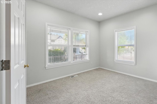 unfurnished room featuring healthy amount of natural light, carpet, baseboards, recessed lighting, and a textured ceiling