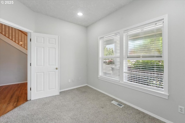 empty room featuring carpet, baseboards, a textured ceiling, and recessed lighting