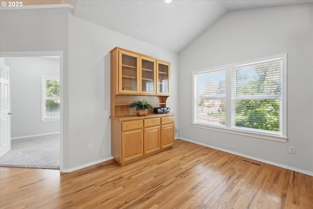 dining area featuring light wood-style flooring, lofted ceiling, and baseboards