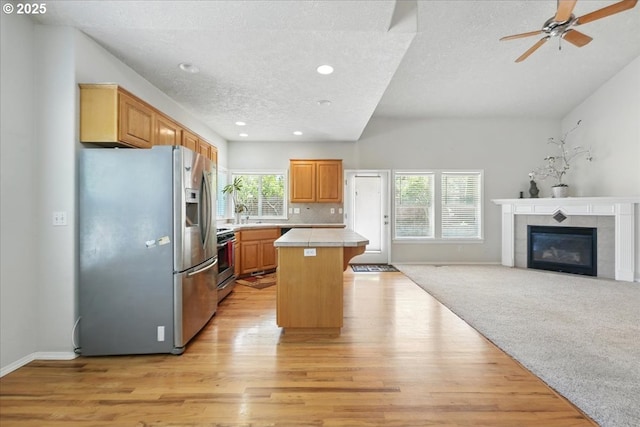kitchen with stainless steel appliances, healthy amount of natural light, light wood finished floors, a center island, and recessed lighting