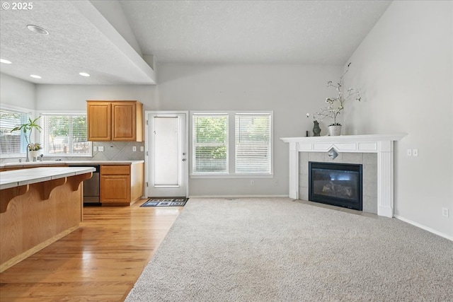 unfurnished living room with a sink, plenty of natural light, a textured ceiling, light wood-type flooring, and a fireplace