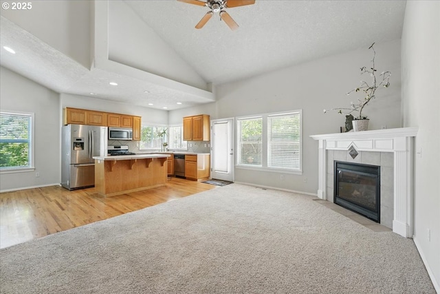 kitchen featuring stainless steel appliances, light carpet, a kitchen island, open floor plan, and lofted ceiling
