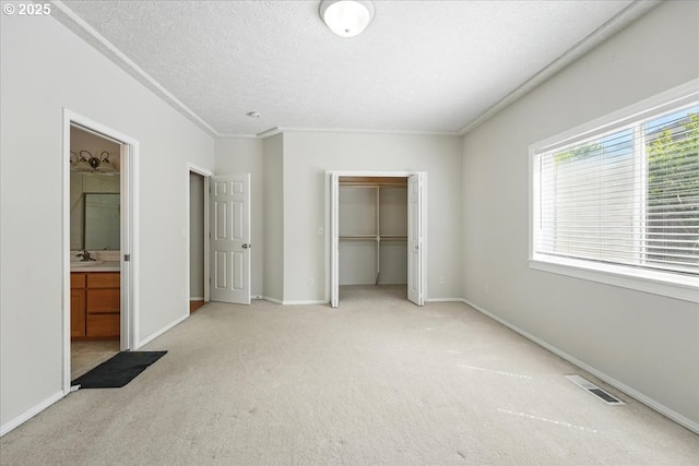 unfurnished bedroom with light carpet, a closet, baseboards, a textured ceiling, and crown molding